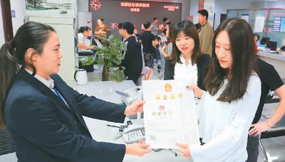 河北省承德市網(wǎng)絡(luò)代購經(jīng)營者陳晨(右)從工作人員手中接過帶有統(tǒng)一社會信用代碼的營業(yè)執(zhí)照。 劉環(huán)宇攝(人民圖片)